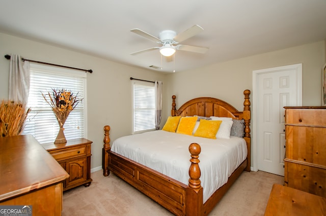 bedroom featuring light carpet, multiple windows, and ceiling fan