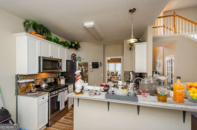 kitchen featuring white cabinetry, appliances with stainless steel finishes, kitchen peninsula, and a kitchen breakfast bar