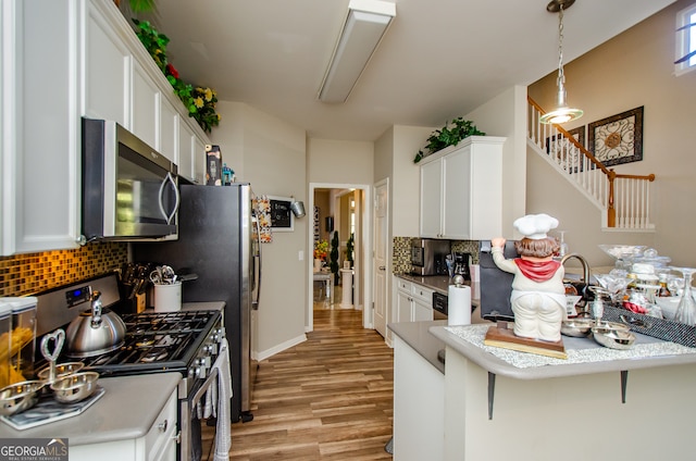 kitchen with a kitchen breakfast bar, kitchen peninsula, white cabinetry, and stainless steel appliances