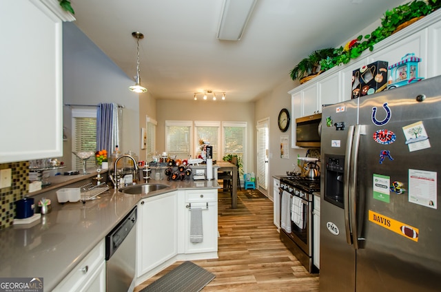 kitchen featuring kitchen peninsula, stainless steel appliances, pendant lighting, white cabinets, and light hardwood / wood-style flooring