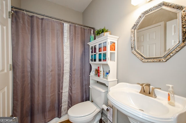 bathroom with toilet, sink, and curtained shower