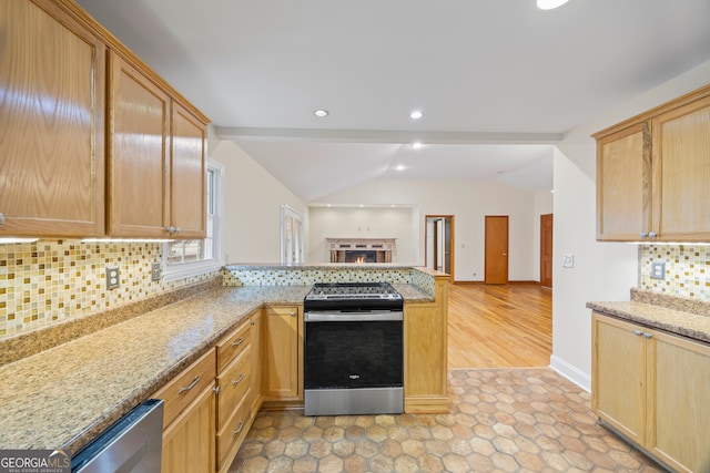 kitchen with lofted ceiling, kitchen peninsula, backsplash, light stone countertops, and stainless steel appliances