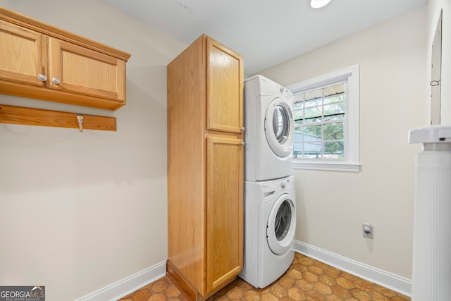 clothes washing area featuring cabinets, stacked washer / dryer, and light tile patterned floors