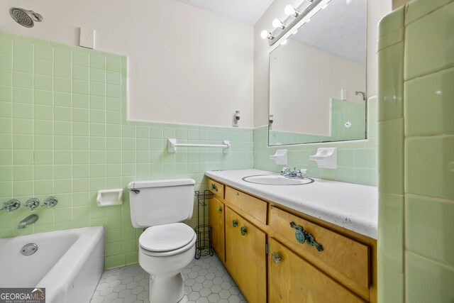 full bathroom featuring toilet, vanity, tile walls, and tile patterned flooring