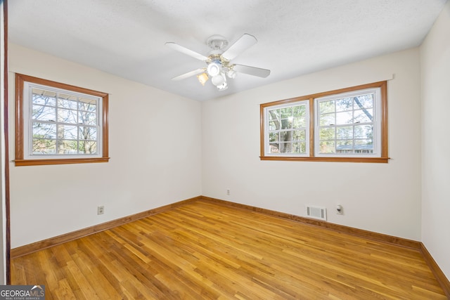 empty room featuring a textured ceiling, light wood-type flooring, and ceiling fan