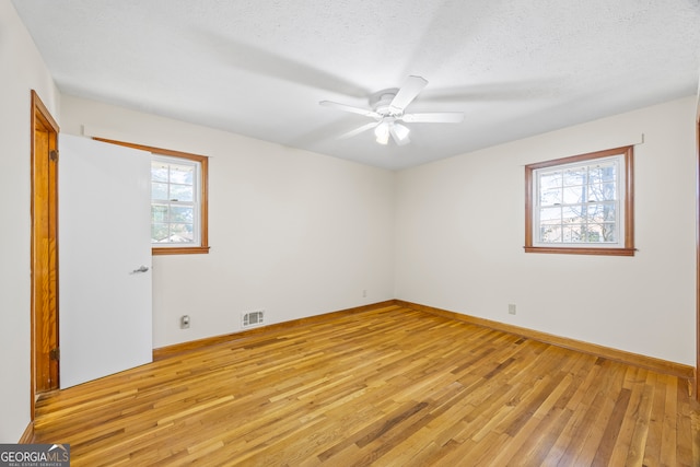 empty room with ceiling fan, a textured ceiling, and light wood-type flooring