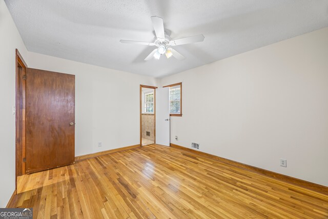 spare room with a textured ceiling, light wood-type flooring, and ceiling fan