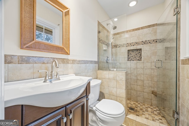 bathroom with toilet, an enclosed shower, vanity, and tile walls