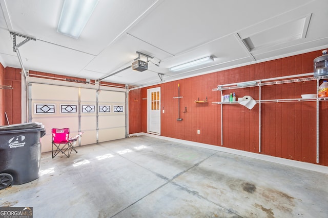 garage with a garage door opener and wood walls