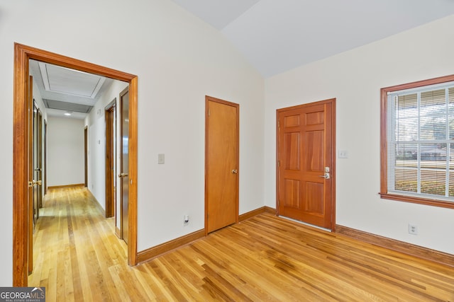 empty room with vaulted ceiling and light hardwood / wood-style flooring