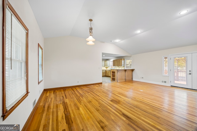 unfurnished living room with light wood-type flooring and vaulted ceiling