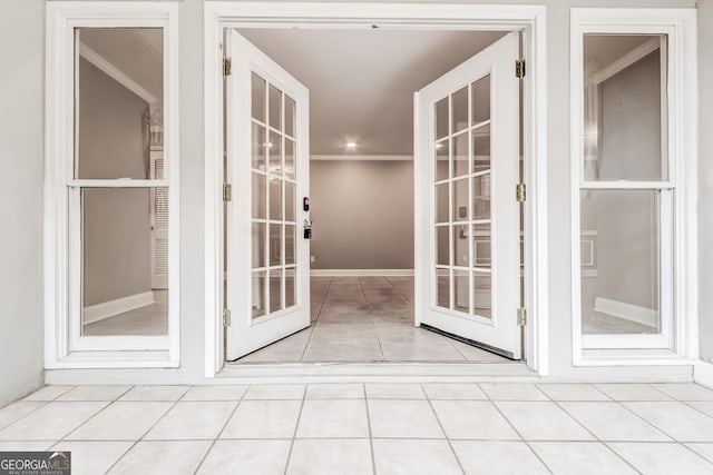 doorway to outside with ornamental molding and light tile patterned floors