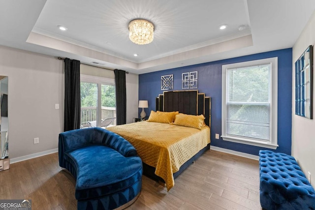 bedroom featuring an inviting chandelier, a tray ceiling, access to outside, and hardwood / wood-style flooring