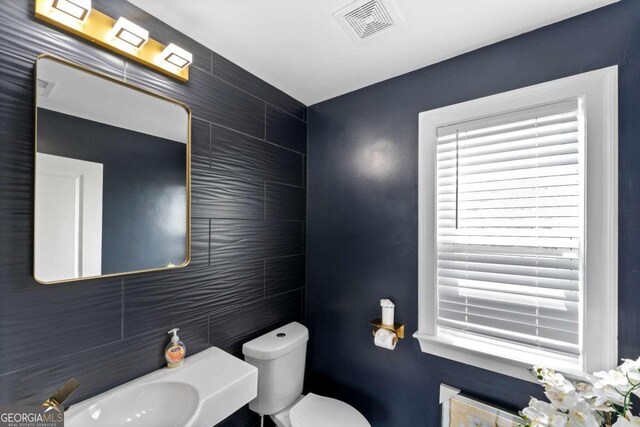 bathroom featuring tile walls and toilet