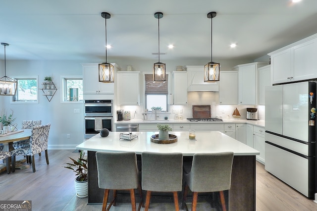 kitchen featuring stainless steel appliances, pendant lighting, and white cabinets