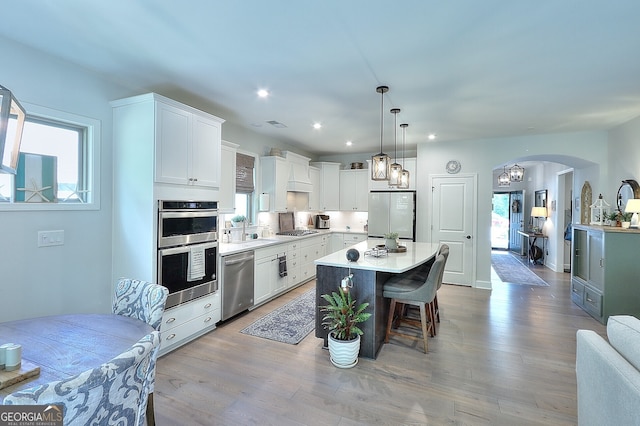 kitchen with light hardwood / wood-style floors, a healthy amount of sunlight, appliances with stainless steel finishes, and a kitchen island