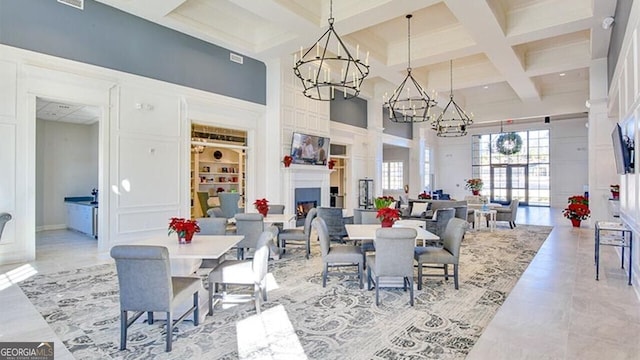 dining room with a towering ceiling, beam ceiling, a chandelier, and coffered ceiling