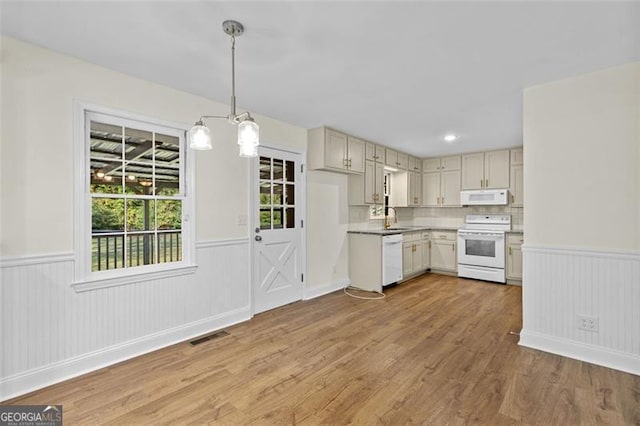 kitchen with decorative backsplash, hardwood / wood-style flooring, hanging light fixtures, sink, and white appliances