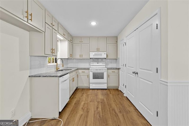 kitchen with white appliances, sink, light stone countertops, white cabinets, and light hardwood / wood-style floors