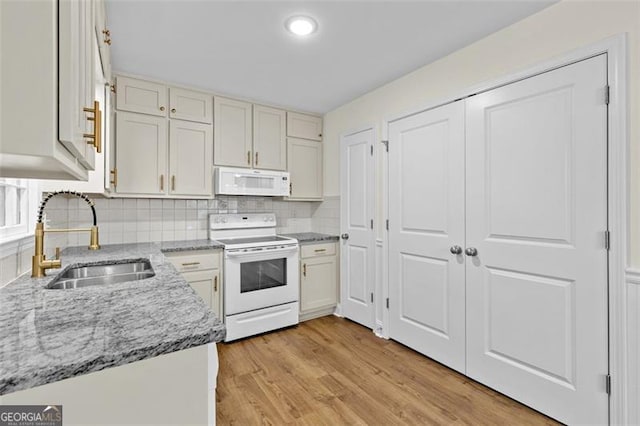 kitchen with backsplash, sink, light wood-type flooring, light stone counters, and white appliances