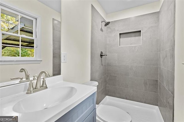 bathroom with vanity, toilet, and a tile shower