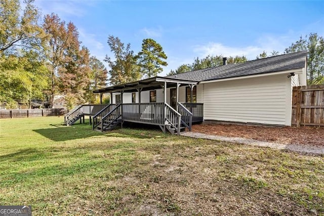 rear view of property with a wooden deck and a lawn