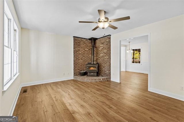 unfurnished living room featuring hardwood / wood-style flooring, a wood stove, and ceiling fan