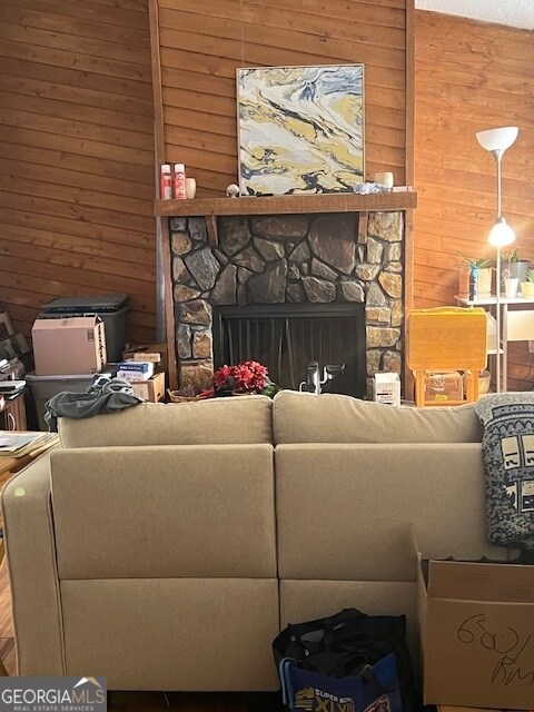 living room with wood walls and a stone fireplace