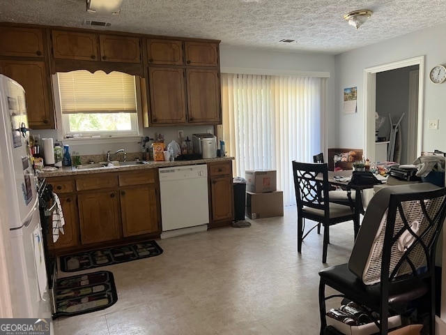 kitchen with white appliances, sink, and a textured ceiling