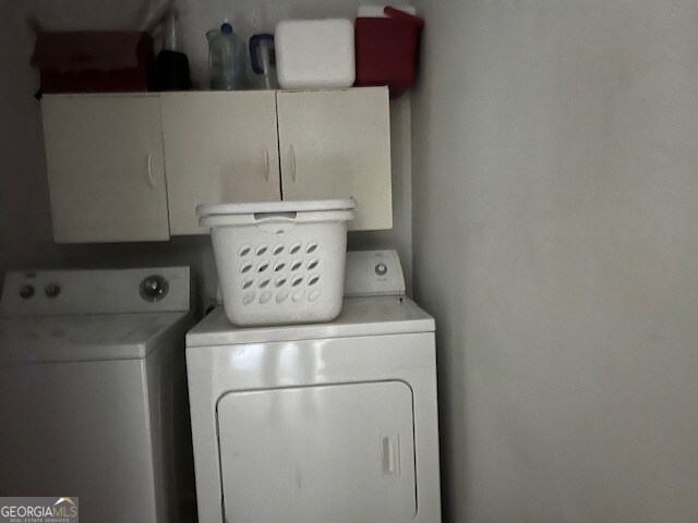 clothes washing area with cabinets and washing machine and clothes dryer