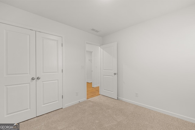 unfurnished bedroom with light carpet and a closet