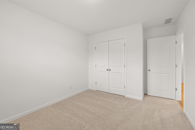 unfurnished bedroom with a closet and light carpet