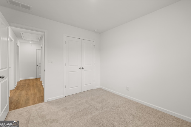 unfurnished bedroom featuring a closet and light colored carpet