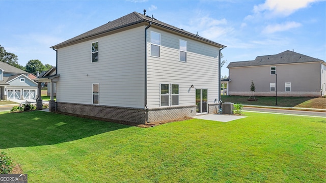 rear view of house featuring cooling unit, a garage, and a lawn