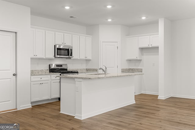 kitchen featuring stainless steel appliances, sink, an island with sink, and white cabinets