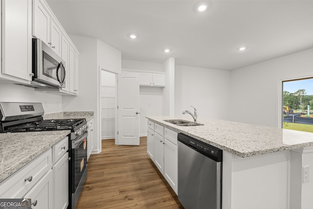 kitchen with dark wood-type flooring, stainless steel appliances, a center island with sink, sink, and white cabinets