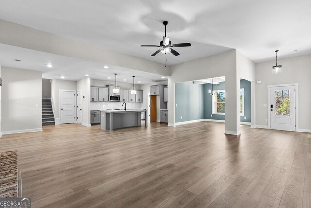 unfurnished living room featuring a fireplace, ceiling fan, light wood-type flooring, and a wealth of natural light