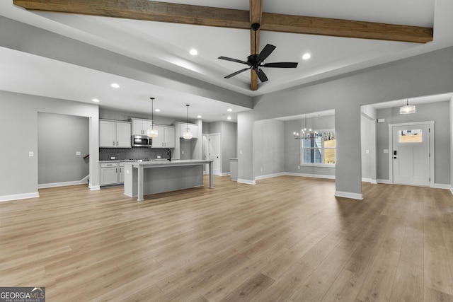 living room with beam ceiling, ceiling fan with notable chandelier, and light wood-type flooring