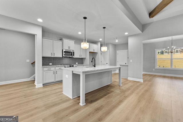 kitchen with a kitchen breakfast bar, white cabinetry, a kitchen island with sink, and appliances with stainless steel finishes