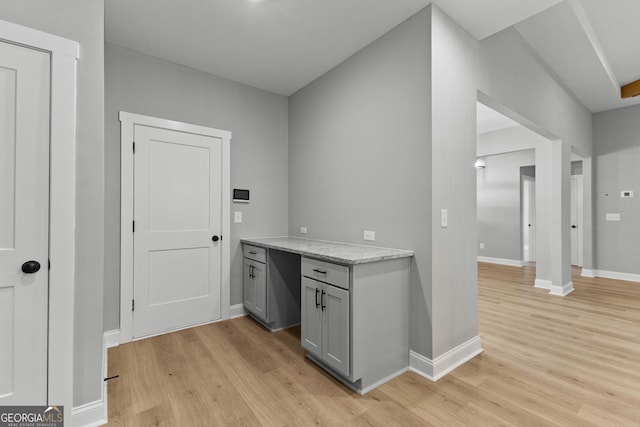 kitchen with gray cabinets, light hardwood / wood-style flooring, and light stone counters