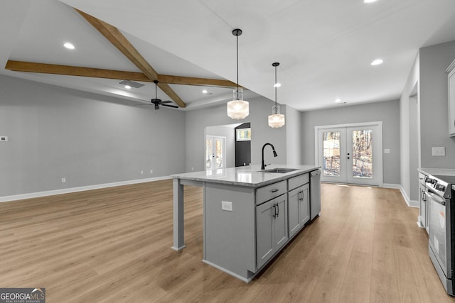 kitchen with french doors, a center island with sink, sink, decorative light fixtures, and stainless steel appliances