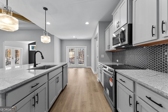 kitchen with french doors, sink, appliances with stainless steel finishes, tasteful backsplash, and light stone counters