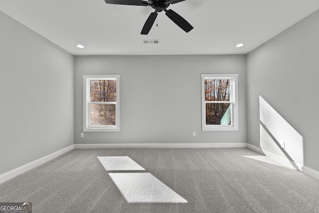 carpeted spare room featuring a wealth of natural light and ceiling fan