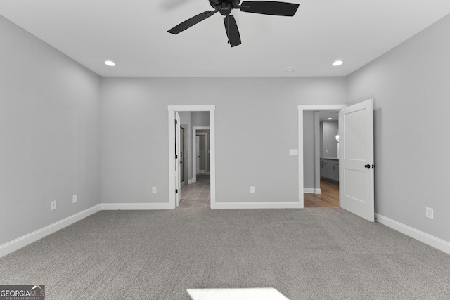 unfurnished bedroom with connected bathroom, light colored carpet, and ceiling fan