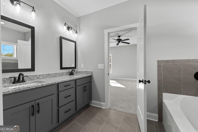 bathroom featuring tile patterned flooring, ceiling fan, vanity, and tiled bath