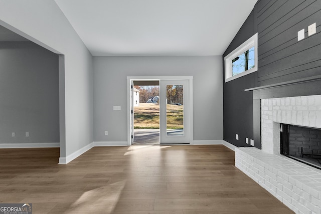 unfurnished living room with wood-type flooring, a fireplace, and vaulted ceiling