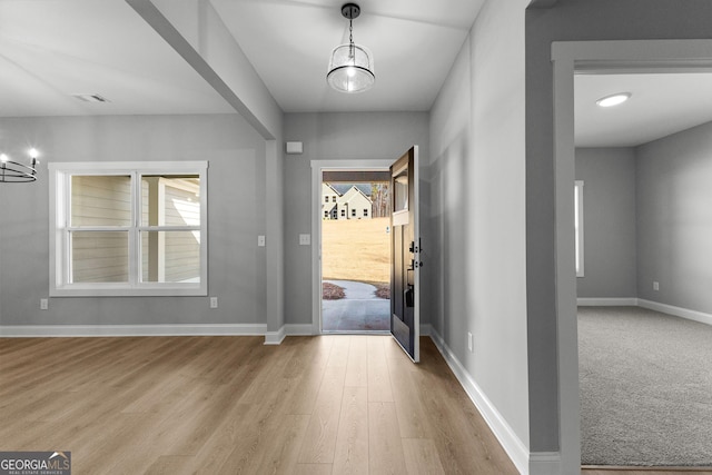 foyer entrance with light hardwood / wood-style floors and an inviting chandelier