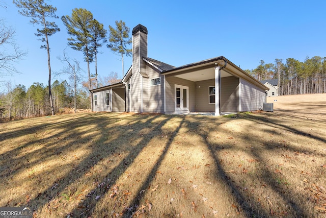 back of property with central air condition unit, french doors, and a yard