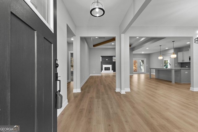 foyer with beam ceiling, sink, light hardwood / wood-style floors, and french doors