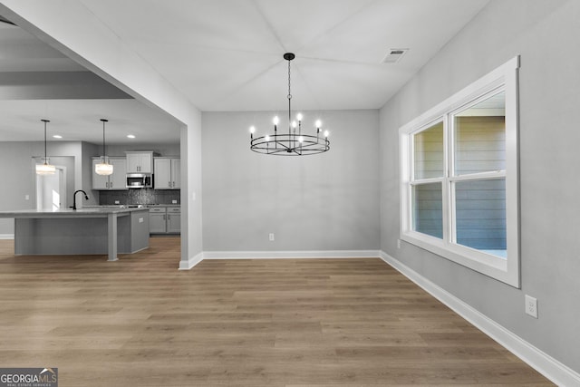 unfurnished dining area with dark hardwood / wood-style floors, sink, and an inviting chandelier